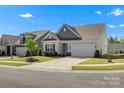 Inviting single-story home with a well-maintained lawn and attached two-car garage on a sunny day at 329 Brambling Ct, Monroe, NC 28110