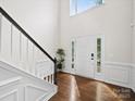 Elegant foyer with hardwood floors, staircase, and natural light flowing through the transom windows at 404 Basingdon Ct, Waxhaw, NC 28173