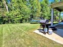 Well-maintained backyard with a gas grill on a concrete patio and a trampoline on the lawn at 413 Hunton Forest Dr, Concord, NC 28027