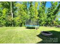 Expansive backyard featuring a trampoline and stone fire pit, perfect for outdoor enjoyment at 413 Hunton Forest Dr, Concord, NC 28027