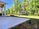Lush backyard view with a trampoline and stone fire pit, extending from a concrete patio at 413 Hunton Forest Dr, Concord, NC 28027
