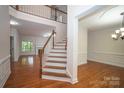 Bright foyer with hardwood floors, staircase with white railings, and views into living and dining rooms at 4410 Laurel Twig Ct, Charlotte, NC 28215