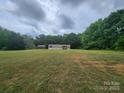 Expansive lawn surrounds this cozy single-story home with a storage shed; trees provide a scenic backdrop at 544 Bentley Rd, Shelby, NC 28152