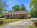Charming one-story brick home featuring a well-maintained lawn, mature landscaping, and cracked driveway at 613 W Pine St, Kershaw, SC 29067