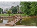 Dock overlooking waterfront home with lush green lawn and surrounding trees, offering a peaceful retreat at 7942 Vista View Dr, Sherrills Ford, NC 28673
