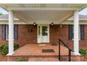 Inviting front porch with brick flooring, white columns, and black shuttered windows at 102 Sussex Ave, Cherryville, NC 28021