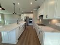 Modern kitchen featuring white cabinets, a large island, stainless steel appliances, and wood-look flooring at 12033 Lavinia Ln, Charlotte, NC 28277