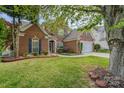 Charming brick two-story home featuring a well-manicured lawn, landscaping, and two car garage at 13406 Ada Ct, Charlotte, NC 28213