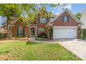 Charming brick two-story home featuring a well-manicured lawn, landscaping, and two car garage at 13406 Ada Ct, Charlotte, NC 28213