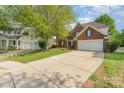 Charming brick two-story home featuring a well-manicured lawn, landscaping, and two car garage at 13406 Ada Ct, Charlotte, NC 28213