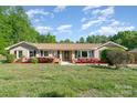 Charming brick home with a well-maintained lawn, flowering shrubs, and classic black shutters at 14834 Pawnee Trl, Matthews, NC 28104