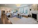 Open-concept living room with fireplace, large windows, and hardwood floors at 15431 Cimarron Hills Ln, Charlotte, NC 28278