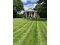 Stately brick home with white columns and meticulously striped lawn creates a grand and inviting curb appeal at 1721 White Pond Ln, Waxhaw, NC 28173