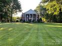 Stately brick home with white columns and expansive lawn framed by mature trees exudes elegance and charm at 1721 White Pond Ln, Waxhaw, NC 28173