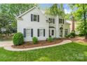 Charming two-story home with a well-manicured lawn, lush landscaping, and a welcoming green front door at 3134 Old Chapel Ln, Charlotte, NC 28210