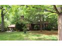 Ranch-style home with mature trees, lush lawn, and carport at 425 Roselawn Pl, Charlotte, NC 28211