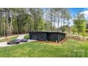 Modern black house surrounded by lush greenery, featuring a flat roof, and a long driveway at 444 Starnes Circle Dr, Taylorsville, NC 28681
