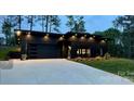 Sleek black home featuring a flat roof, stylish garage door, and modern outdoor lighting at 444 Starnes Circle Dr, Taylorsville, NC 28681