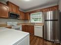 Functional kitchen featuring wooden cabinets, white appliances, and durable wood-look flooring at 4609 Coronado Dr, Charlotte, NC 28212