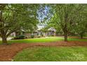 Beautiful brick home featuring a well-manicured lawn and mature trees providing shade at 8368 Fairfield Forest Rd, Denver, NC 28037