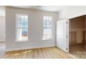 Bright bedroom with wood floors, two windows, and white door leading to additional storage space at 9612 Pointer Rd # 59, Huntersville, NC 28078