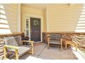 Inviting front porch with seating, a wreath on the door, and stone accents at 9930 Karras Commons Way, Matthews, NC 28105