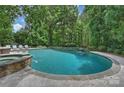 Inviting backyard pool and spa featuring stone accents and lush landscaping for privacy at 12028 Royal Lytham Ct, Charlotte, NC 28277