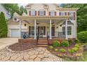 Inviting front porch with decorative columns, fan, seating, and charming landscaping at 13312 Edgetree Dr, Pineville, NC 28134