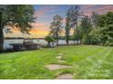 Scenic backyard view leading to a lake, showcasing a well-maintained lawn, a dock, and mature trees at 17112 Green Dolphin Ln, Cornelius, NC 28031
