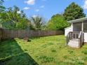Lush backyard with a wooden fence, a fire pit, and access to a screened in back porch at 620 Third St, Rock Hill, SC 29730