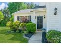 Inviting home entrance featuring a landscaped garden and a classic, paneled front door at 7128 Rock Bass Ct, Concord, NC 28025