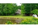 Picturesque backyard featuring a lush lawn, mature trees, tranquil pond, and charming wooden bridge at 9013 Yellow Pine Ct, Waxhaw, NC 28173