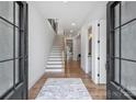 Bright foyer showcasing hardwood floors, a staircase with wood treads and white risers, and modern lighting at 910 Everett Pl, Charlotte, NC 28205