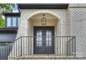 Charming front entrance with an arched brick porch, black wrought iron railings, and double glass doors at 910 Everett Pl, Charlotte, NC 28205