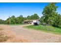 Exterior view of home featuring long gravel driveway, windmill and a trailer at 130 Helen Dr, Statesville, NC 28625