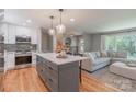Open-concept kitchen with a gray island, stylish pendant lights, and an adjacent living room at 2009 Edgewater Dr, Charlotte, NC 28210