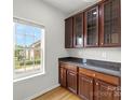 Butler's pantry with granite countertops, dark wood cabinetry, and natural light from a window at 2151 Belle Vernon Ave, Charlotte, NC 28210