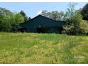 Exterior view of a traditional barn featuring a star decoration and overgrown foliage at 4194 Buffalo Shoals Rd, Maiden, NC 28650