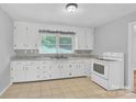 Bright kitchen with white cabinets, tile flooring, and ample countertop space at 735 Wilbrown Cir, Charlotte, NC 28217