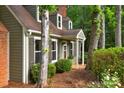 Close-up of the home's exterior with green siding and brown shutters, surrounded by nature at 8400 Prince Valiant Dr, Waxhaw, NC 28173
