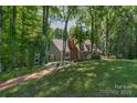 Scenic view of a home in the woods with a large green lawn and brick walkway at 8400 Prince Valiant Dr, Waxhaw, NC 28173