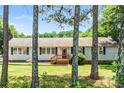 Charming single-story home with neutral siding, dark shutters, a wood porch, a well-manicured lawn and mature trees at 10230 Hagers Rd, Huntersville, NC 28078