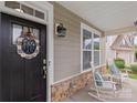 Cozy front porch featuring rocking chairs, stone accents, and a decorative wreath on the black front door at 108 Wrangler Dr, Mooresville, NC 28115