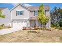 Charming two-story home with gray siding, a two-car garage, well-manicured lawn and freshly landscaped flowerbeds at 112 Tanner Loop, Troutman, NC 28166