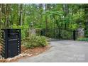 Home entrance features an ornate black metal gate with stone pillars, a lamp post, and a neatly maintained driveway at 115 Forestcliff Ne Ct, Concord, NC 28025