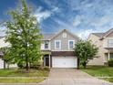 Two-story home with grey siding and stone accents over the garage at 1523 Loropetalum Rd, Charlotte, NC 28215