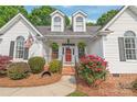 Inviting front porch with rocking chairs, a red door, and lush landscaping, creating a warm and welcoming entrance at 1542 Crowders Woods Dr, Gastonia, NC 28052