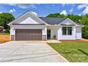 Beautiful one-story home showcasing white siding, a brown garage door, and a concrete driveway at 3300 Travis Nw Ln, Concord, NC 28027
