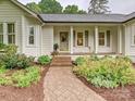Close up view of a charming home exterior featuring a brick walkway, manicured garden beds, and covered entry at 3610 Mill Pond Rd, Charlotte, NC 28226