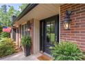 Close-up of a classic black front door framed by brick, decorative lighting, and vibrant greenery at 530 Bonita Dr, Landis, NC 28088